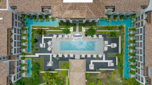 Top down view of a pool with palm trees, benches, and cabanas